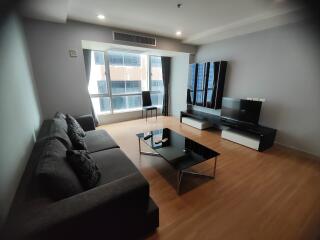 modern living room with large window, sofa, TV, and coffee table