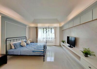 Modern bedroom with bed, TV, and window