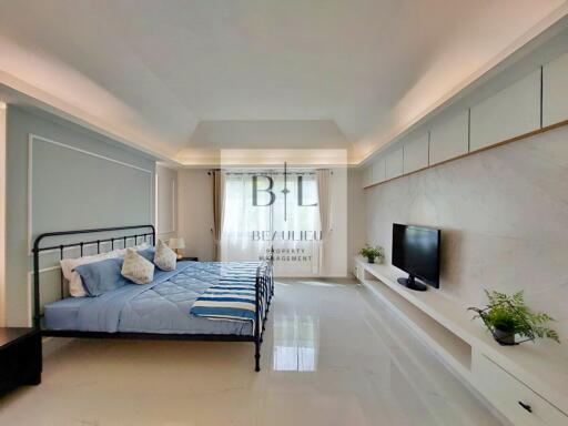 Modern bedroom with bed, TV, and window
