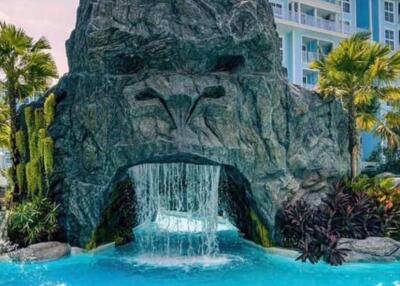 Outdoor pool area with rock waterfall and nearby modern buildings