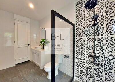 Modern bathroom with glass shower and patterned tile wall