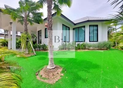 Exterior view of a house with a well-maintained garden and palm trees