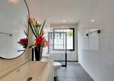 Modern bathroom with large mirror, stylish basin, and decorative plants