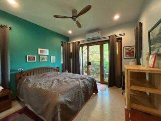 Cozy bedroom with green accent wall and balcony access