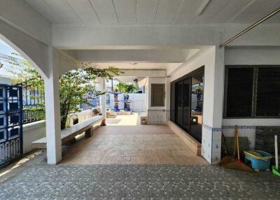 Covered outdoor area with tiled flooring, seating bench, and surrounding greenery