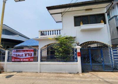 Front view of a house for sale with a sign and contact numbers