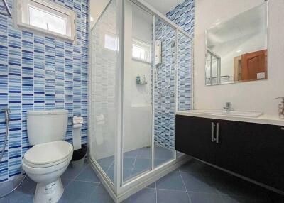 Modern bathroom with glass-enclosed shower, toilet, and vanity