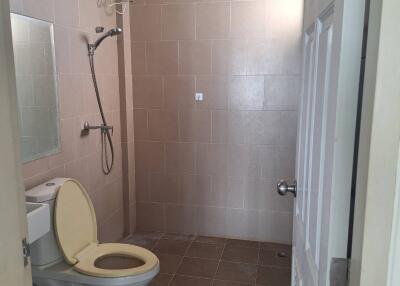 Bathroom with toilet, shower, and tiled walls