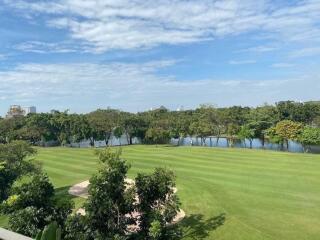 View of a green lawn with trees and a river