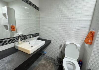 Modern bathroom with white tiles, a sink, and a toilet