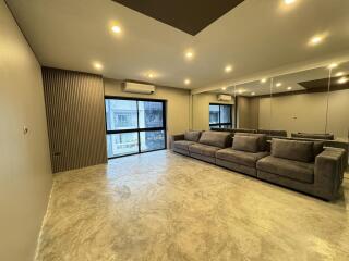 Spacious modern living room with large gray sectional sofa and mirrored wall