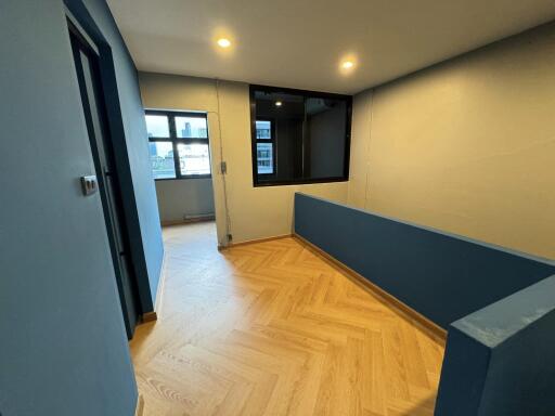 Well-lit hallway with wooden flooring and blue accent wall