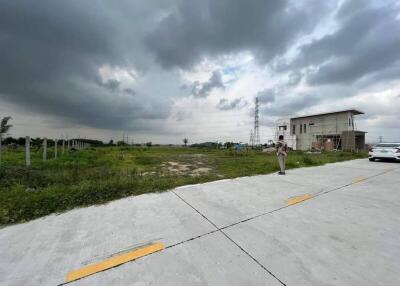 view of empty land with a small building and cloudy sky