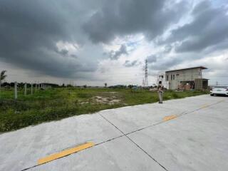 view of empty land with a small building and cloudy sky