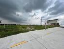 view of empty land with a small building and cloudy sky