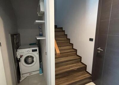 Laundry area with washing machine next to a staircase