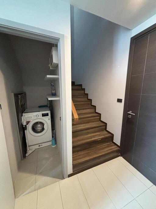 Laundry area with washing machine next to a staircase