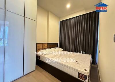 Spacious bedroom with bed, wardrobe, and large window with curtains