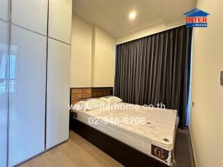 Spacious bedroom with bed, wardrobe, and large window with curtains