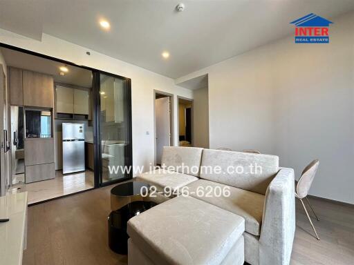 Modern living room with furniture and kitchen area in the background