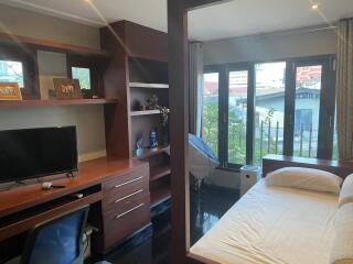 Modern minimalist bedroom with a small workspace and large windows.