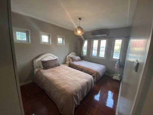 Bedroom with two beds, windows, and a hanging light fixture