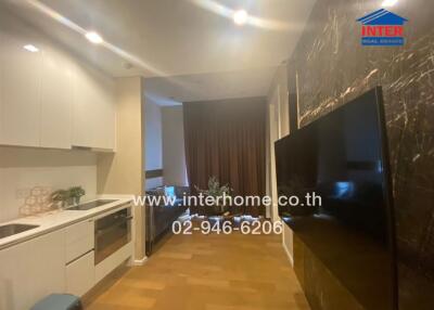 Modern kitchen with sleek white cabinets and a large flat-screen TV