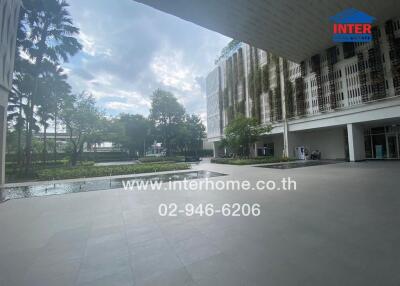 Exterior view of a building with a paved patio, greenery, water feature, and modern architecture