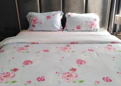 A bedroom with a neatly made bed featuring floral bedding.