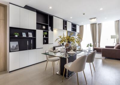 Modern open-plan living and dining area with built-in shelves, glass dining table, and comfortable seating