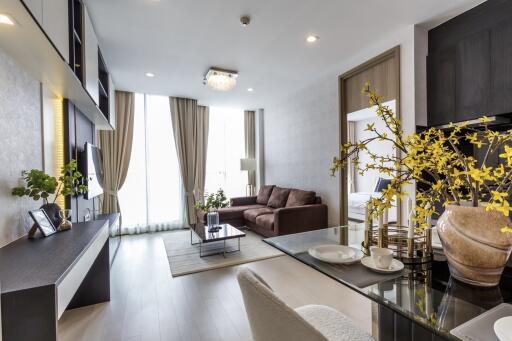 Modern living room with glass dining table, brown sofa, and large window with curtains