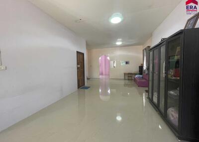 Spacious living room with tiled flooring, wooden door, and display cabinet