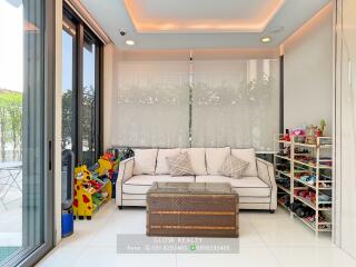 Modern living room with large windows and a mix of indoor plants and children