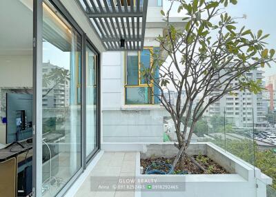 Modern apartment balcony with glass doors, greenery, and city view
