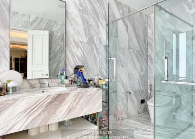 Modern bathroom with marble walls, large vanity, and glass-enclosed shower