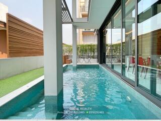 Outdoor pool area with greenery and patio seating