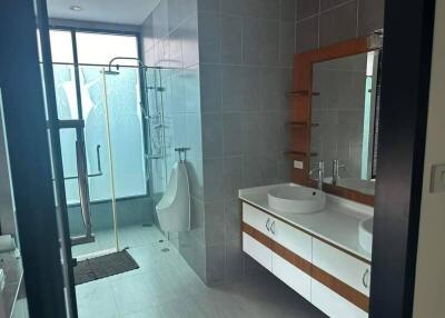 Modern bathroom with glass shower, urinal, and large vanity mirror