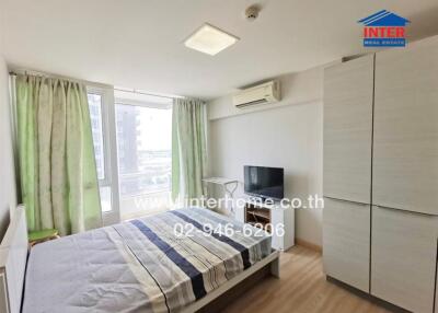 Well-lit bedroom with a large window, bed, TV, and wardrobe