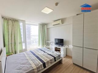 Well-lit bedroom with a large window, bed, TV, and wardrobe