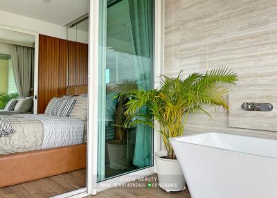 Bedroom with sliding glass door to a bathroom featuring a large bathtub and potted plant.