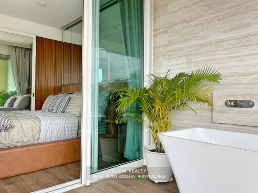 Bedroom with sliding glass door to a bathroom featuring a large bathtub and potted plant.