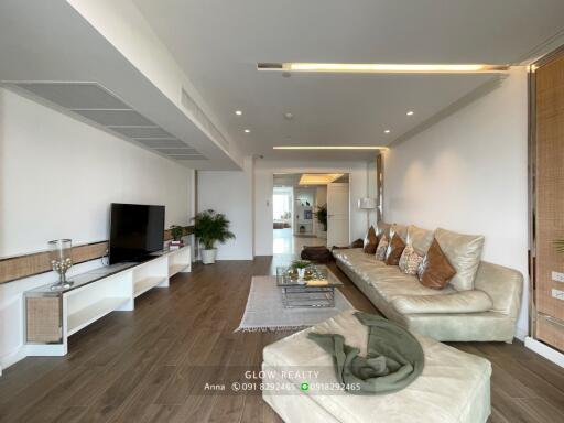 Modern living room with wooden flooring, white shelves, and a comfortable beige sofa.