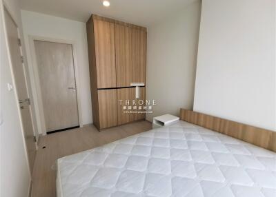 Bedroom with a wooden wardrobe and a bed with a white mattress.