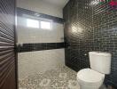 Modern bathroom with dark tiles and patterned flooring