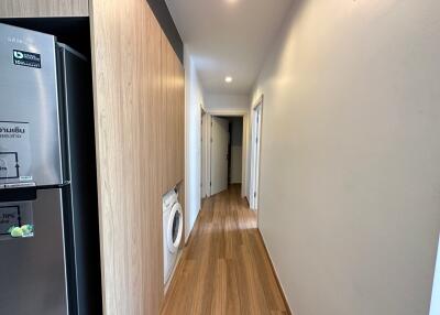 View of a modern hallway with wooden flooring, concealed washer-dryer and multiple doors leading to other rooms