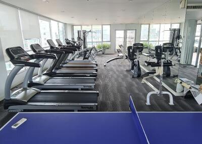 Modern gym with treadmills, exercise machines, and a ping pong table