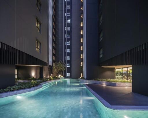 Night view of a modern high-rise apartment building with a swimming pool