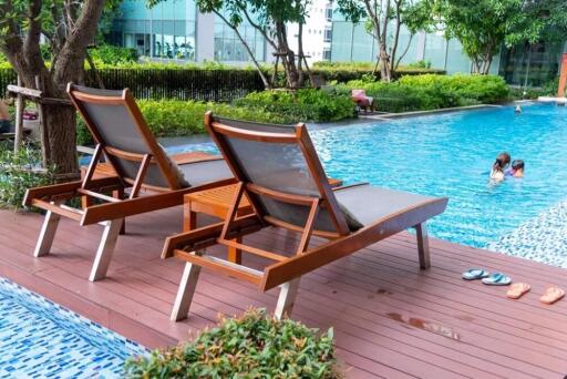 Outdoor pool area with lounge chairs and people swimming