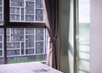 Bedroom with window view of nearby buildings