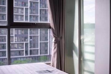 Bedroom with window view of nearby buildings